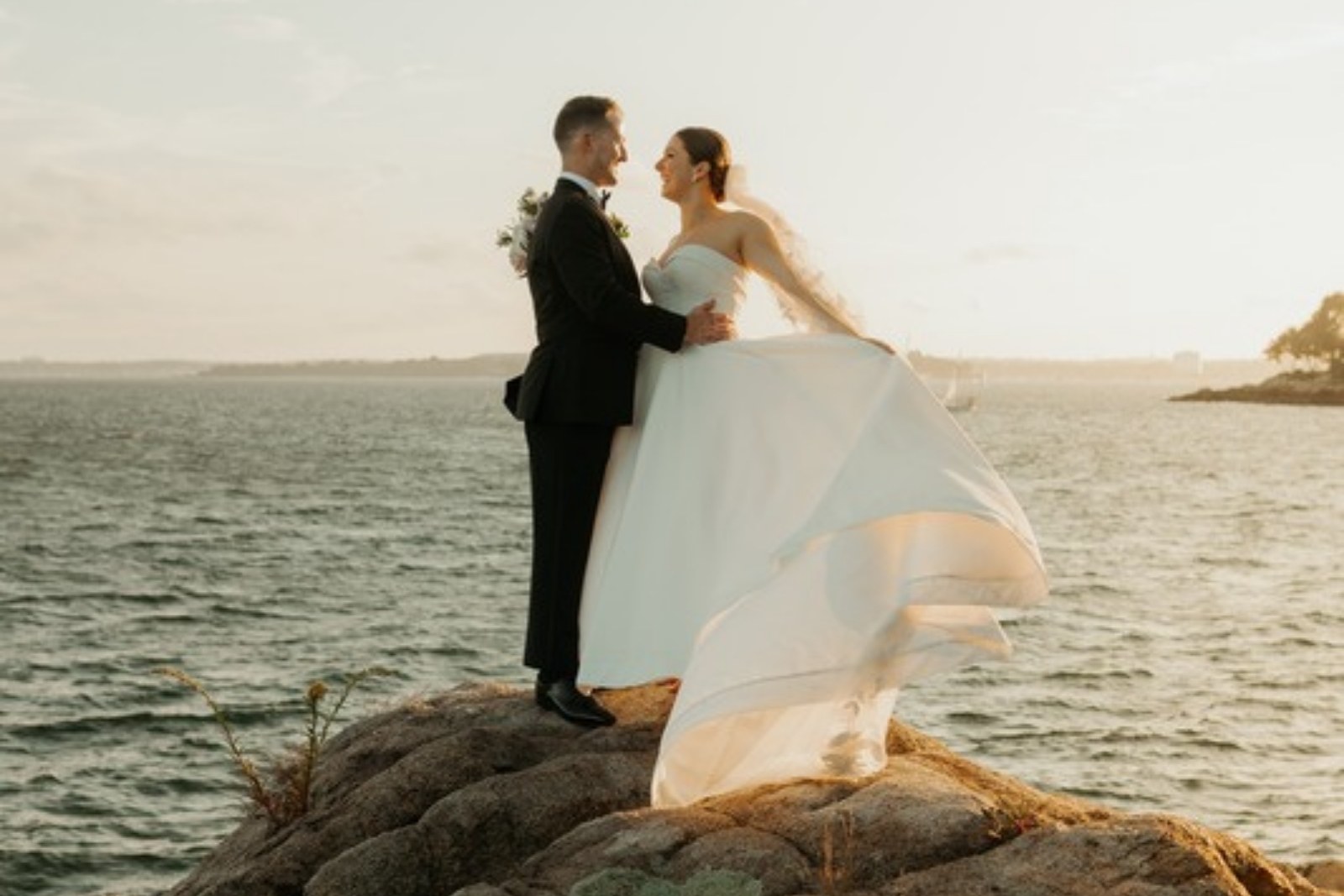 Wedding couple embracing on seaside rocks in New England at golden hour